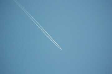 Plane on blue sky with large tail contrail behind - travel at high altitude