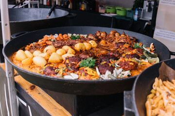 Cooking in a large cauldron dishes. Delicious food cooked over an open fire, which is offered at a street food fair, event, festival.