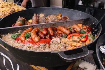 Cooking in a large cauldron dishes. Delicious food cooked over an open fire, which is offered at a street food fair, event, festival.