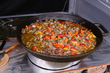 Cooking in a large cauldron dishes. Delicious food cooked over an open fire, which is offered at a street food fair, event, festival.