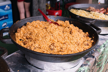Cooking in a large cauldron dishes. Delicious food cooked over an open fire, which is offered at a street food fair, event, festival.