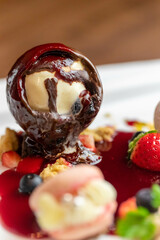 クリスマスプレートのチョコドームにストロベリーヒットソースをかける
