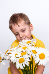 A cute boy with a beautiful bouquet of large daisies. Portrait of a child, funny and cute facial expression. Selective focus.