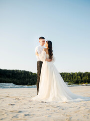 Fototapeta na wymiar Young couple hugging in a sand quarry, wedding day