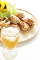 Barbecue chicken drumsticks on wooden plate and glass of beer