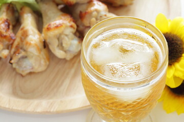 Barbecue chicken drumsticks on wooden plate and glass of beer