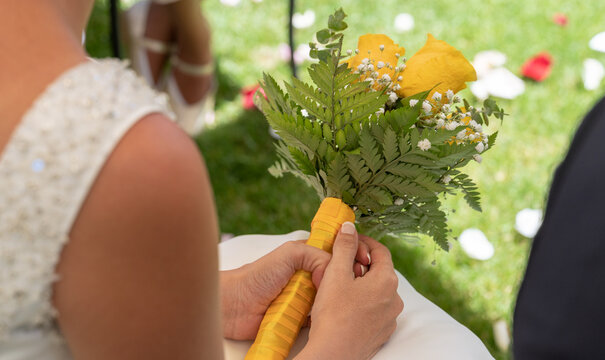 Image with bride holding in her hands bouquet of yellow roses at wedding ceremony