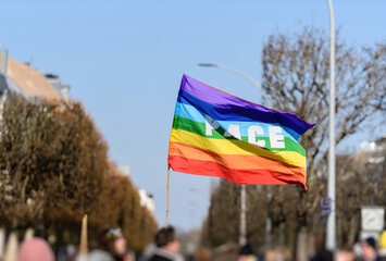 Beautiful rainbow LGBTQI flag waving in the wind with large PEACE word in the middle - city street perspective