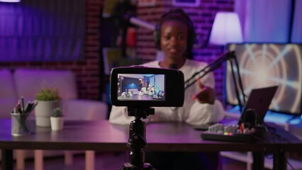 Selective focus on digital video camera screen recording african american vlogger talking to audience from home podcasting studio. Influencer filming herself doing live broadcast for social media.