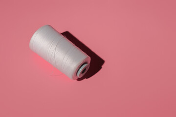 spool of white threads on a colored background with copy space