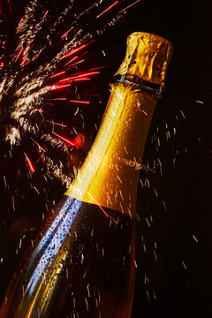 Bottle of champagne against exploding fireworks