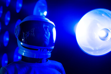 Contemplative woman with space helmet by blue illuminated light
