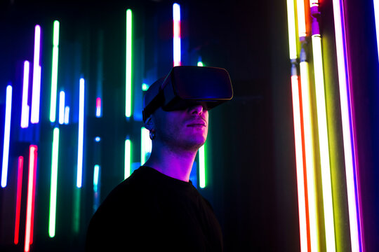 Man wearing VR glasses near multi colored illuminated lights