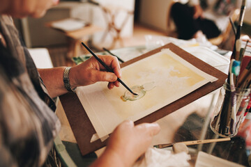 Senior artist painting with paintbrush at home