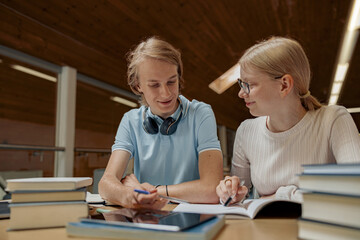 Students sit in the library and take notes while preparing for the exam