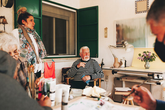 Thoughtful senior man sitting with artists at home