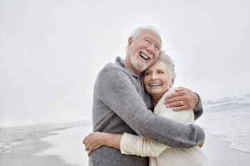 Laughing senior couple embracing at the sea