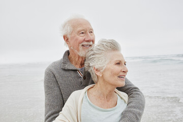Happy senior couple standing smiling on windy beach