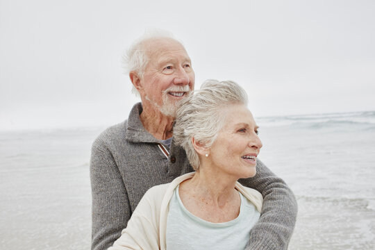 Happy senior couple standing smiling on windy beach