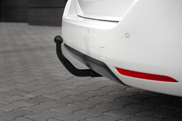 Compact white executive car. Rear parking sensors and towbar on a car, black steel part.
