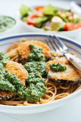 Dish with home made breaded eggplant with spinach pesto, served on spaghetti