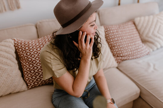 Young woman sitting on a sofa talking on the phone