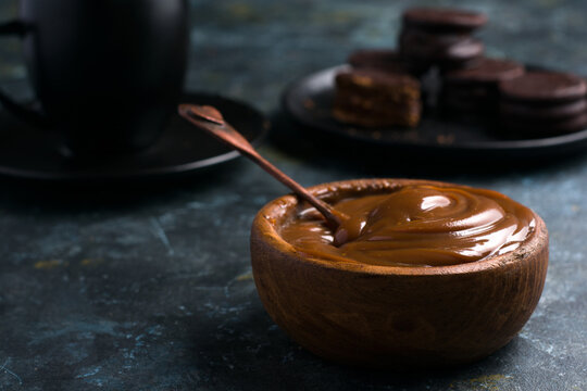 Dulce de leche mixed against cup and saucer near alfajores