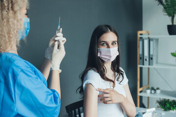Female doctor preparing coronavirus vaccine for woman patient at vaccination center. Medicine...