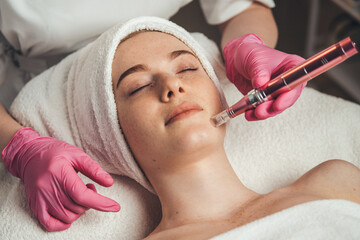 Woman getting facial treatment of chin zone with derma pen at spa salon. Skin treatment. Medicine...