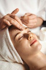 Beautician applying cosmetic cream on patient's face at spa salon. Happy face. Skin treatment....