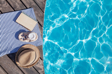 Book, coffee and sun hat near swimming pool