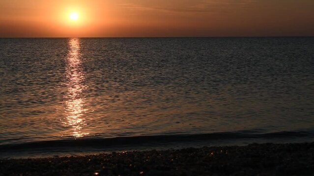 Deep blue water waves splashing on coast of Possidi cape beach at sunset. Beautiful and large yellow sun over mediterranean sea.