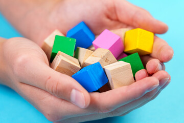 Educational wooden colorful toy blocks close-up on blue background in hands