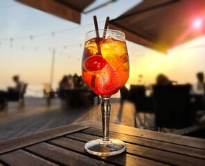 glass of fruit water  aperol on wooden  table on beach cafe at sunset on sea