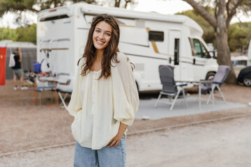 Attractive young caucasian woman looks at camera, spends her weekend camping. Brunette wears casual...
