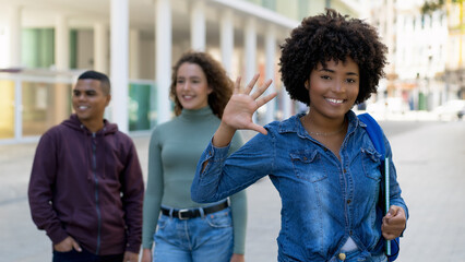 Pretty african american female student with backpack and group of international students