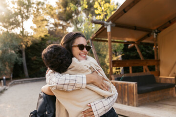 Happy young caucasian women hugging spending leisure time on vacation near campsite. Brunettes wear casual spring clothes. Positive emotions concept