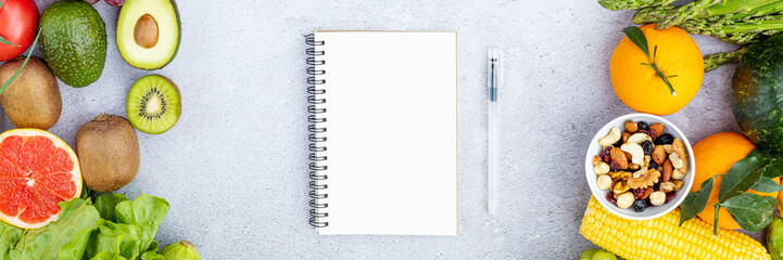 Flat lay top view of paper blank for weekly meal plan on gray background with fresh fruits and vegetables. Calories control, meal plan, food diet and weight loss concept. Horizontal banner for web