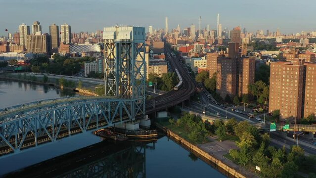 Cinematic tilting pan follows commuter train which snakes out of Harlem Manhattan NYC across the Park Ave Bridge towards The Bronx