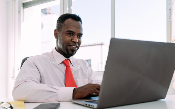 Content ethnic businessman using laptop in office