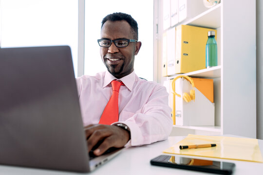 Content ethnic businessman using laptop in office
