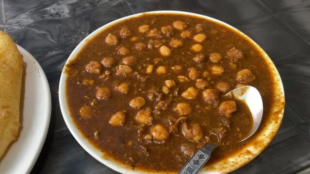 Chole Bhature in Punjabi. Indian-style cooked chickpeas in close-up. Indian food for breakfast With mixed pickles and thinly sliced onions