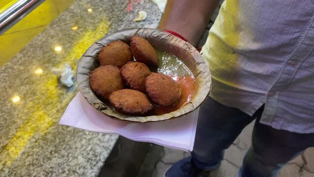 Man holding Indian lentil fritters cooked with yellow moong dal and a few other basic ingredients are known as Moong Dal Bhaaji, Moong Dal Vada, and Moongode.