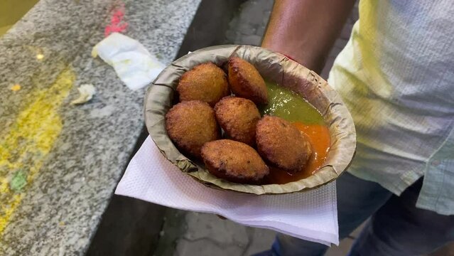 Video of a man holding special Yellow Split Gram Fritters, Mungdal Bhajiya, Pakoda, Dalwada, Pakora, or Moong Dal Vada served with Green Chutney.