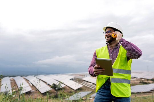 Cheerful foreman talking on radio near solar power plant