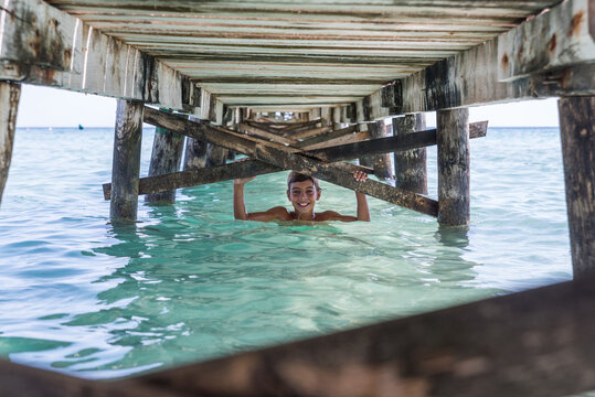 Smiling Boy Under Pier In Sea