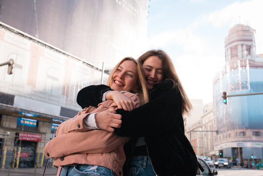 Happy women hugging on street during city stroll