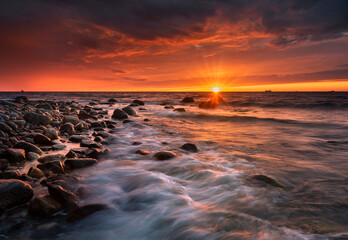 Morze bałtyckie - wschód słońca na plaży Gdynia Orłowo z widokiem na fale i kamieniste...