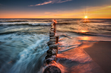 Morze bałtyckie. Plaża w miejscowości Chałupy - półwysep helski, o wschodzie słońca. Duże fale, piasek, wybrzeże, słońce, woda i falochron