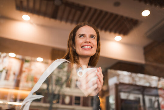 Happy woman with cup of coffee resting in cafe